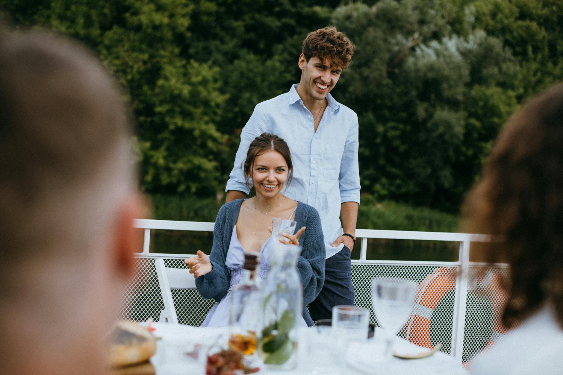 Uśmiechnięta para rozmawia przy kolacji ze znajomymi na dworze