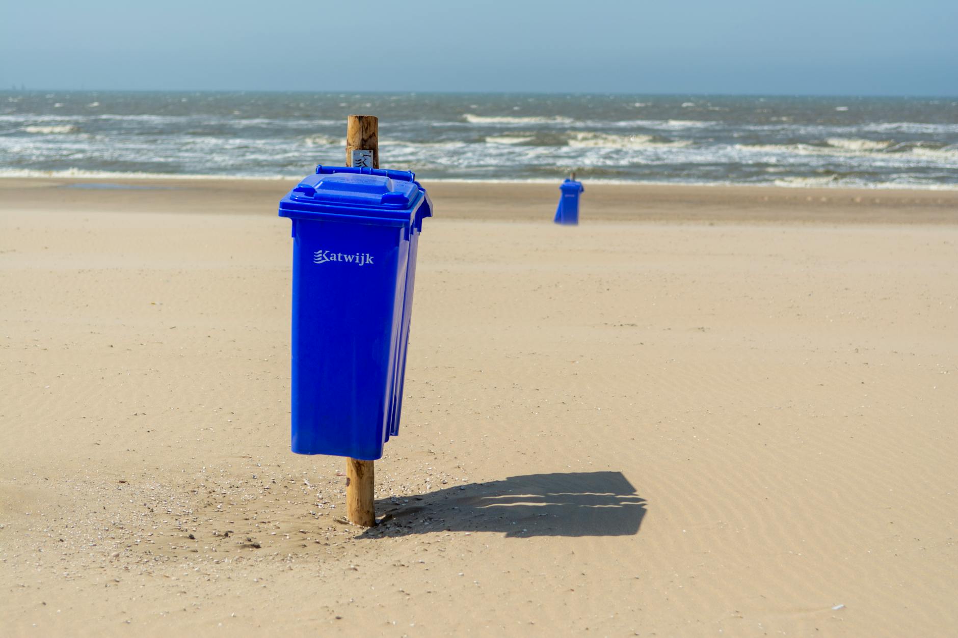 Słoneczna plaża w Katwijk aan Zee z niebieskimi koszami na śmieci