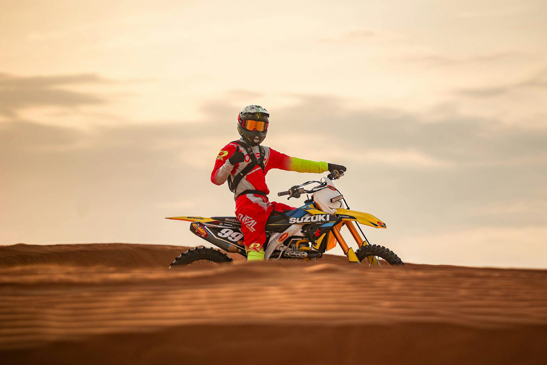 Motocyklista motocrossu na pustynnych wydmach o wschodzie słońca